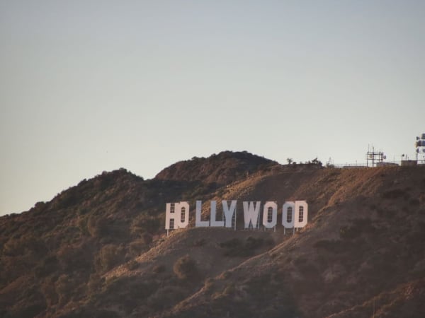 Large white Hollywood letters on a hillside with a tower near Griffith Observatory.