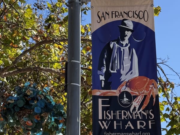 Street lamp with Fisherman's Wharf banner amid autumn trees in San Francisco