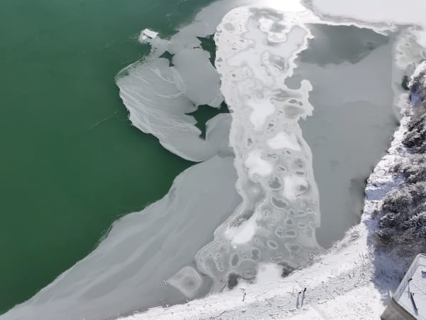 Aerial view of a partially frozen lake and snow at Lake Sylvenstein.