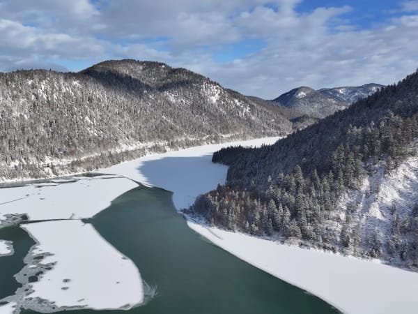Aerial perspective of a frozen lake and mountains at Lake Sylvenstein.