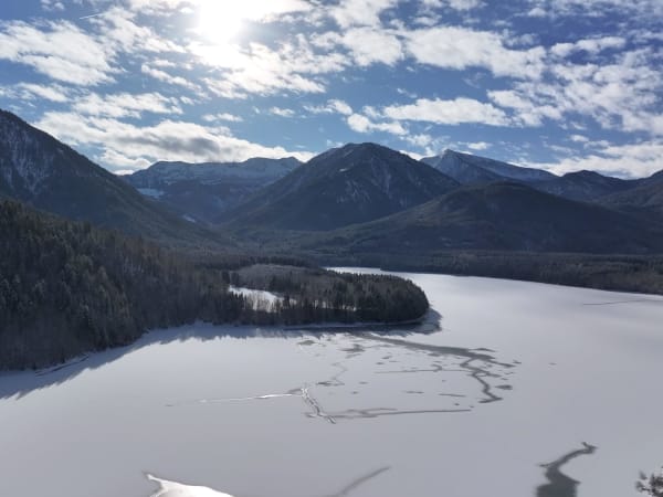 Frozen Sylvenstein Reservoir with snow-covered landscape and surrounding mountains in Bavaria, Germany