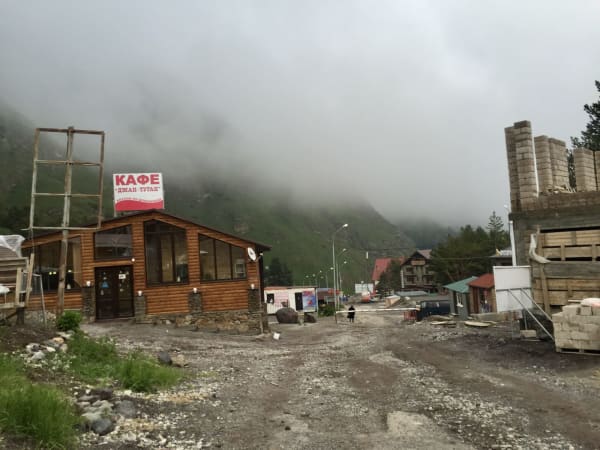 Rustic log-clad cafe with Cyrillic sign and gravel forecourt, Mount Elbrus Expedition