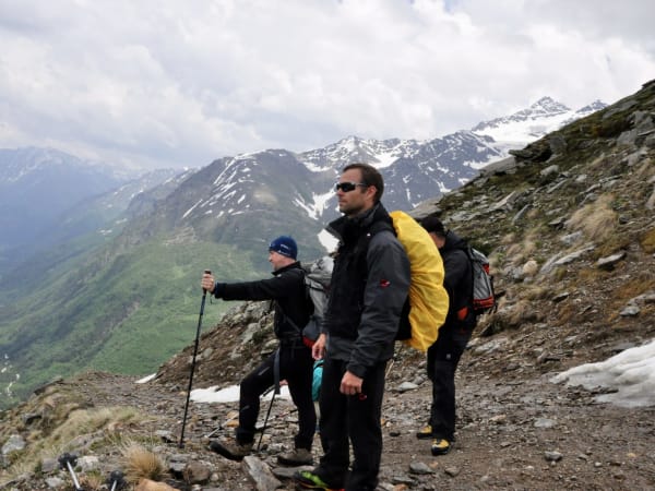 Three hikers with backpacks and trekking poles on rocky Mount Elbrus Expedition trail