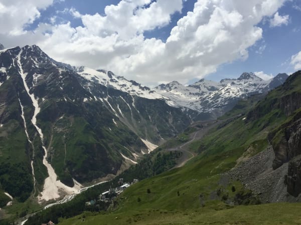 Snow-streaked rocky peaks over alpine meadows and valley buildings, Mount Elbrus Expedition