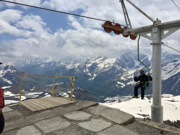 Person on open chairlift at Mount Elbrus Expedition high-altitude station above snow-covered range