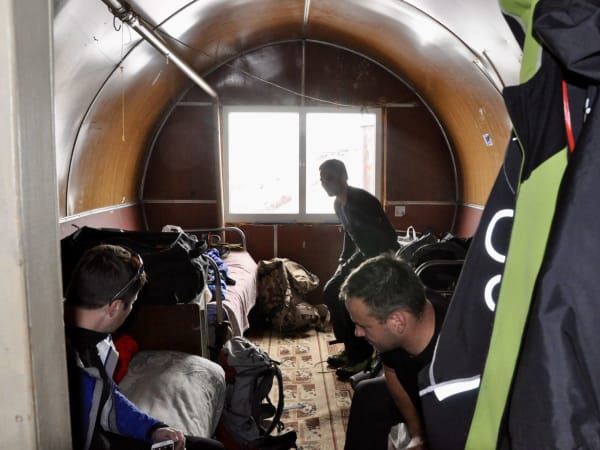 Crowded barrel shelter interior with bunk beds and mountaineers, Mount Elbrus Expedition