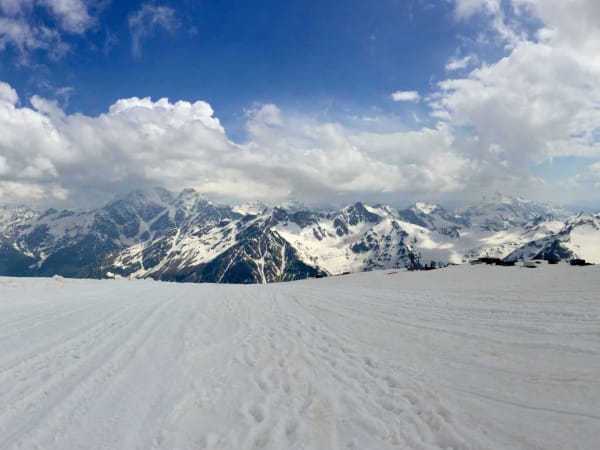 Snow-covered high-altitude plateau with compacted tracks and rocky peaks, Mount Elbrus Expedition