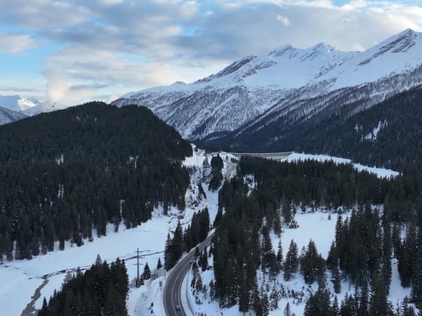 Snow-covered alpine valley with conifer forest and winding road near San Bernardino