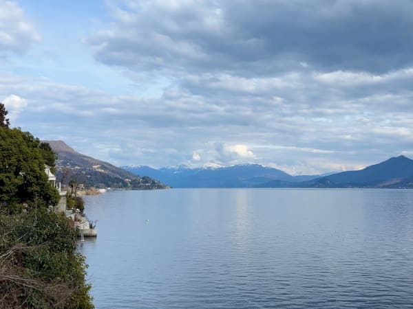 Calm lake water with snow-capped mountains and stone waterfront in Verbania