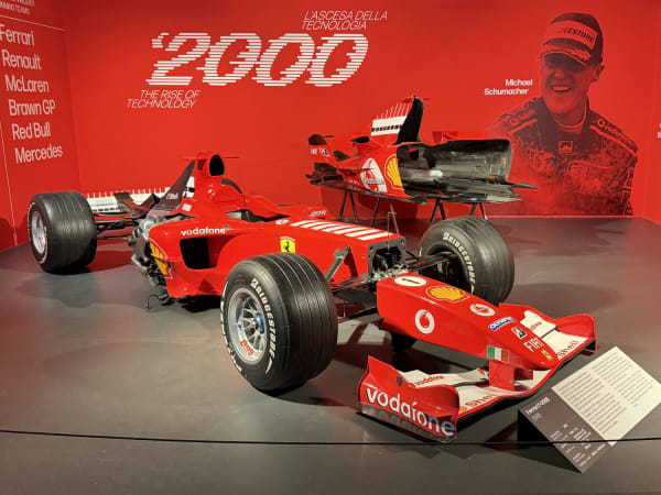 Red Formula 1 car on circular platform inside Turin museum with red walls