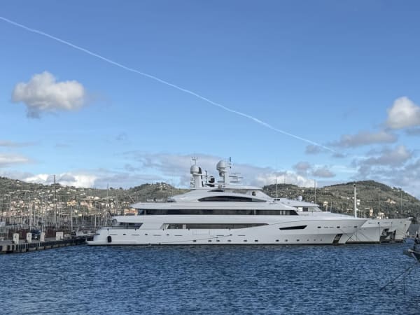 White yacht docked in an Imperia harbor with hills in the background