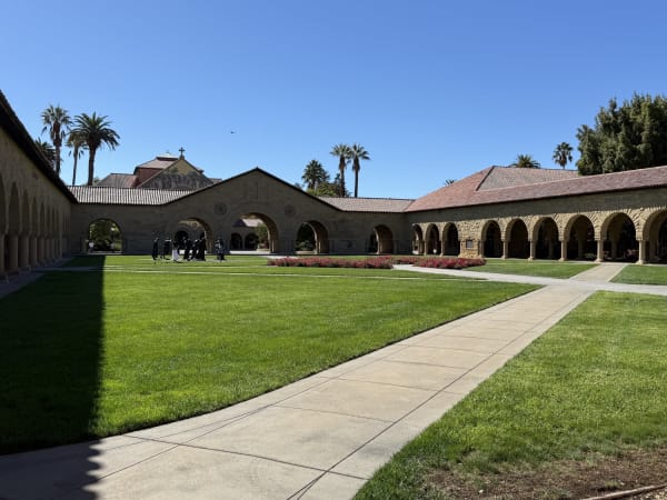 Courtyard with arched colonnades, lawn, palm trees at Stanford University