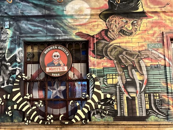 Wall mural featuring horror film characters and a barred window in La Candelaria