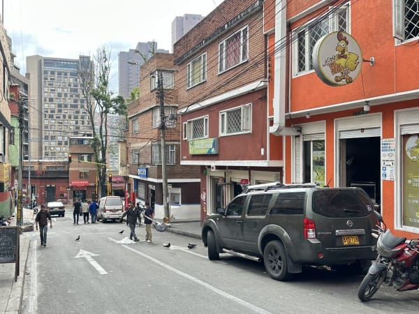 Narrow Zona T & Chapinero street with brick buildings, pedestrians, and modern towers beyond
