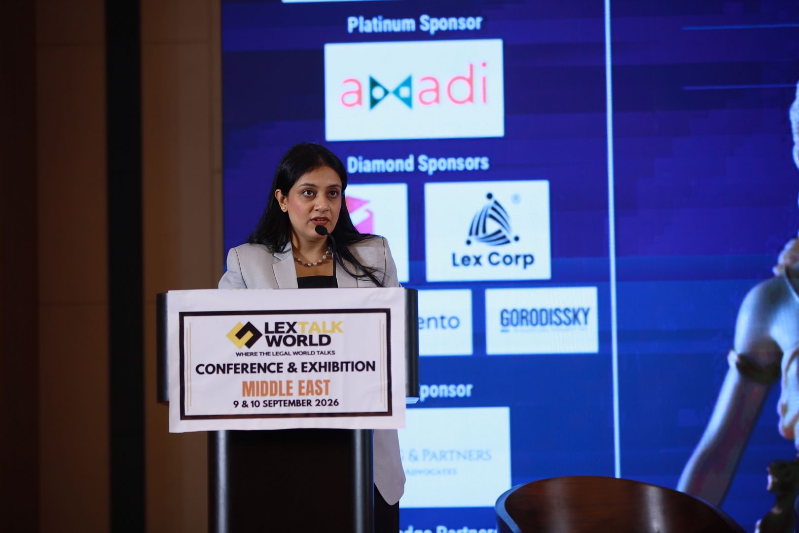 A speaker at the LexTalk World Conference & Exhibition Middle East podium, 9 & 10 September 2026, in front of the sponsor wall
