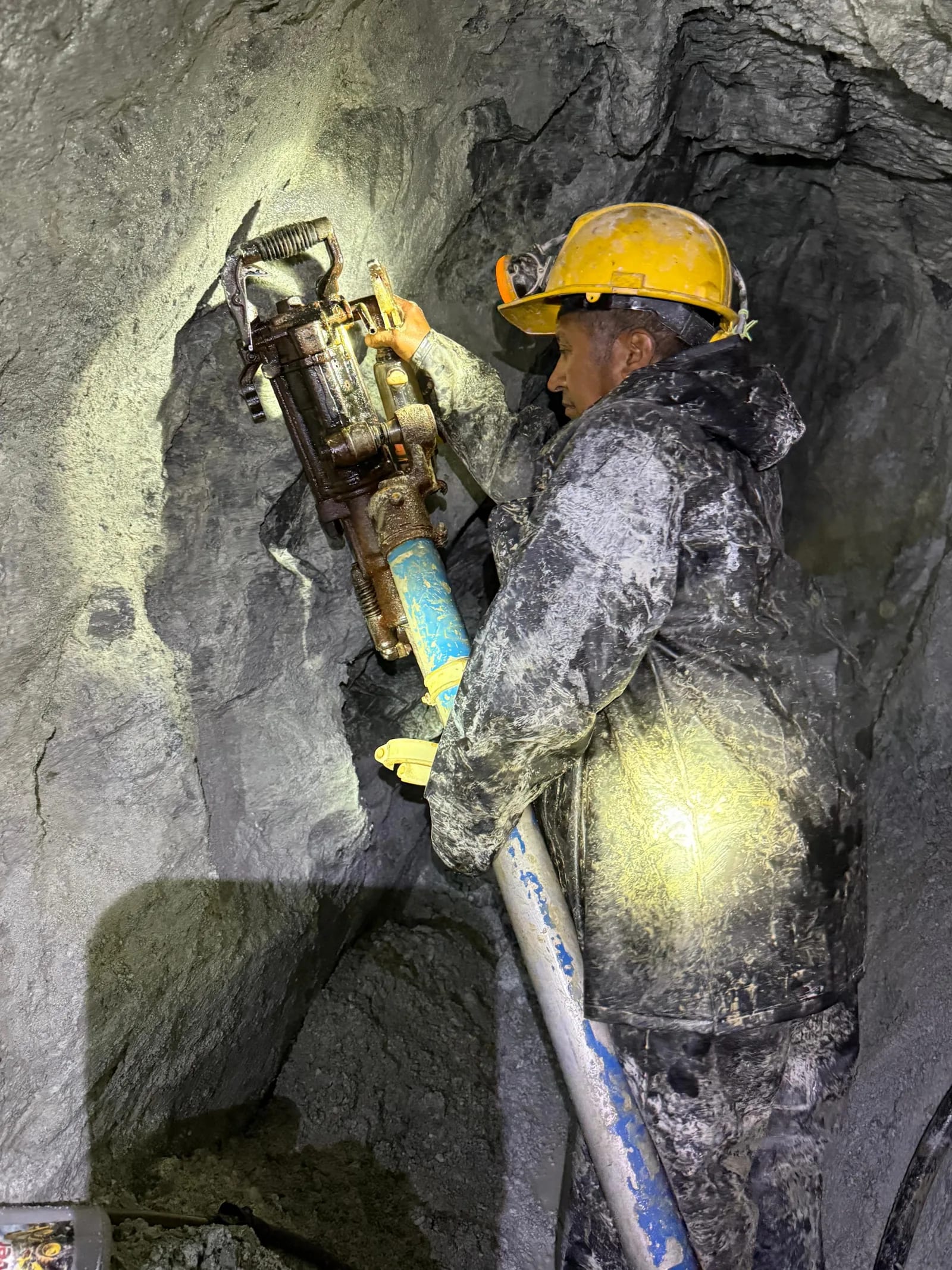 Minero operando perforadora neumática en el frente de explotación.