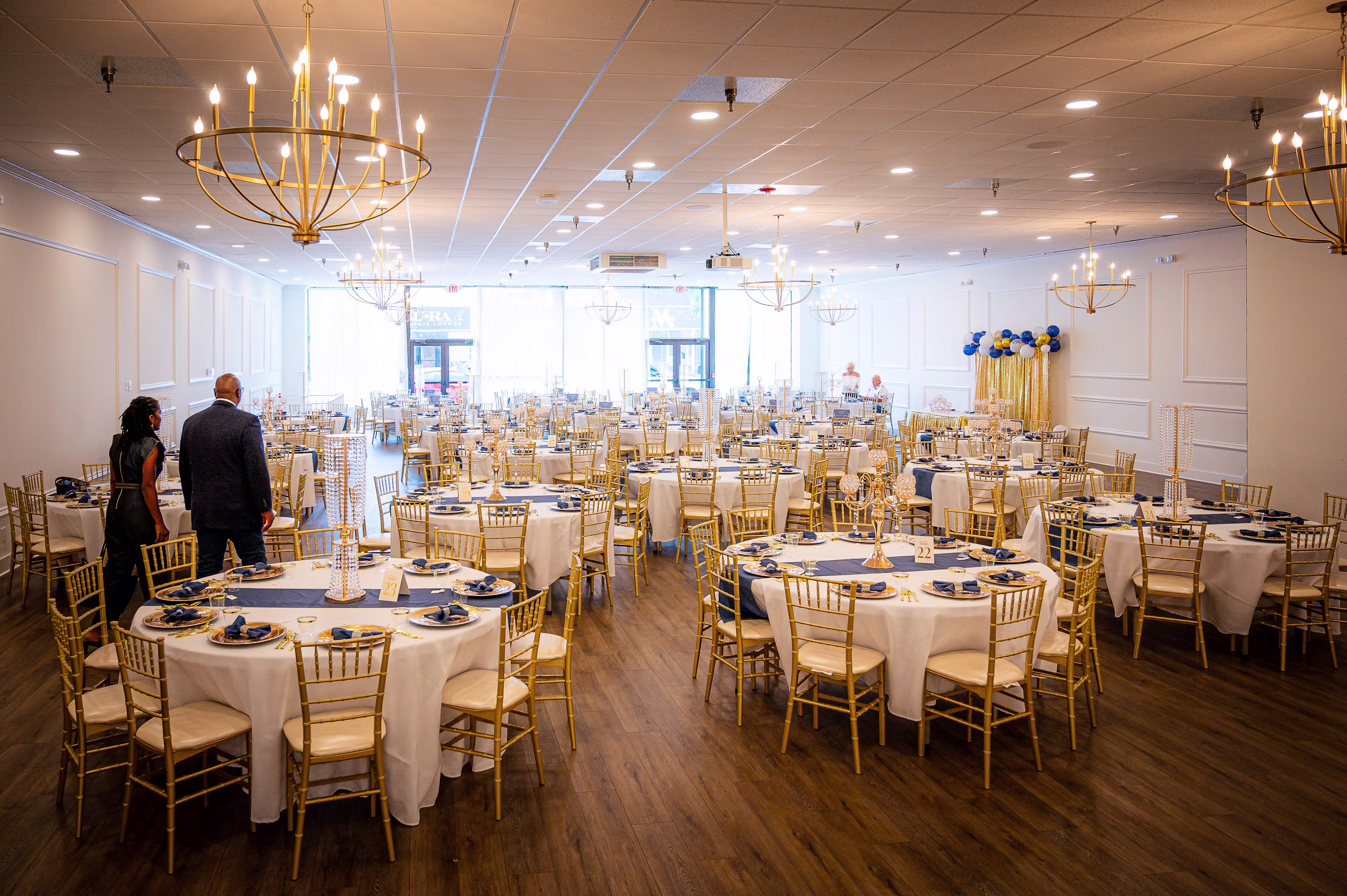 Elegant banquet hall with round tables and gold chairs for a luxury event by Mariveno