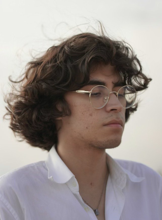 Dramatic editorial shot of men's tousled texture perm, windswept curl