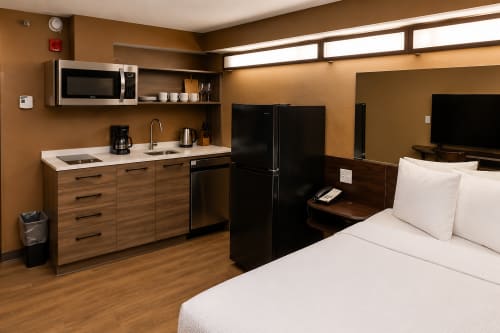Microtel Williston Queen Kitchenette Suite — room layout from entrance showing TV, work desk, kitchenette and queen bed