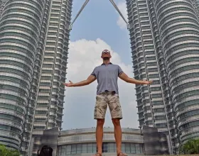 Adrian Bienias stojący po wieżami Petronas Towers w Kuala Lumpur w Malezji