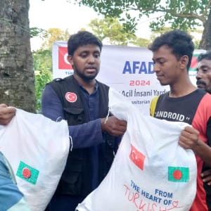 Several men in blue, one holding a red and white bag, appear to be receiving aid.