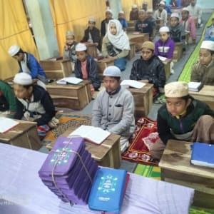 Children sitting at wooden desks in a classroom setting, likely a religious school.