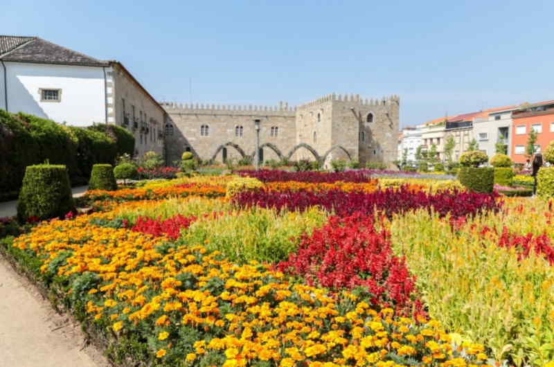 A vibrant garden filled with colorful flowers, with a majestic castle visible in the background.