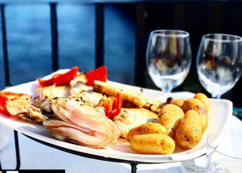 A plate of gourmet food accompanied by a glass of red wine and two elegant wine glasses on a table.
