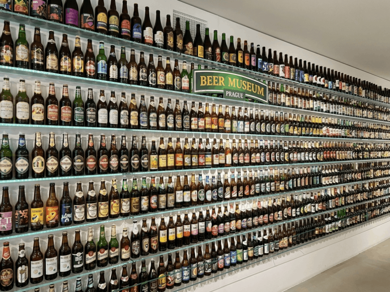 Rows of Czech beer bottles displayed on glass shelves at Beer Museum Prague, showcasing some of the best Czech beers.