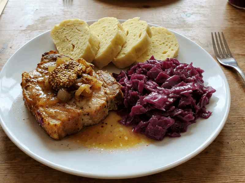 Plate of vepro knedlo zelo, Czech roast pork with bread dumplings and braised red cabbage with mustard seeds.