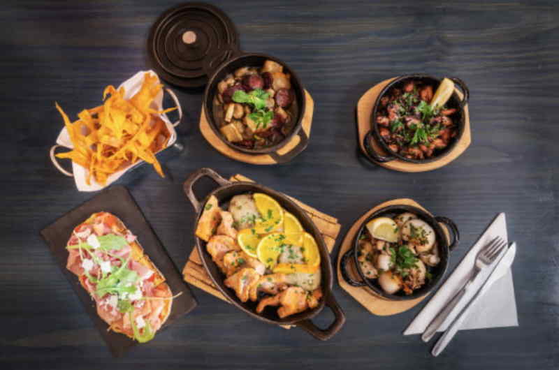 A table is set with various dishes, accompanied by forks and knives, ready for a meal.