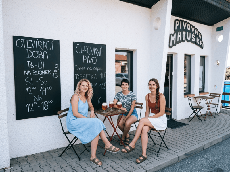 Three women enjoying glasses of beer outside Pivovar Matuška, a craft brewery known for some of the best Czech beers.