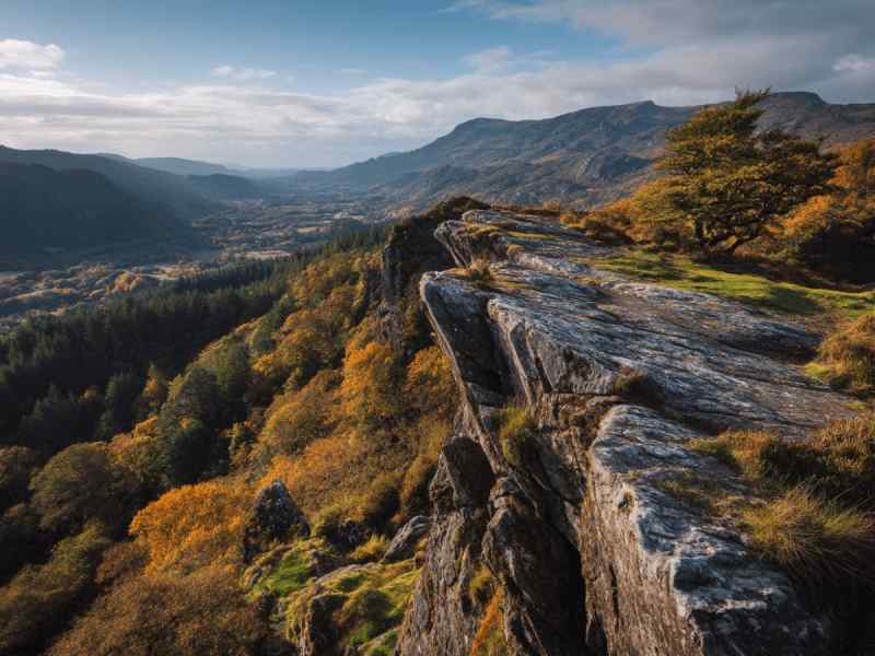 Panoramic view from Eagle’s Nest Lookout overlooking a valley of golden autumn trees, rugged cliffs, and distant mountain peaks.