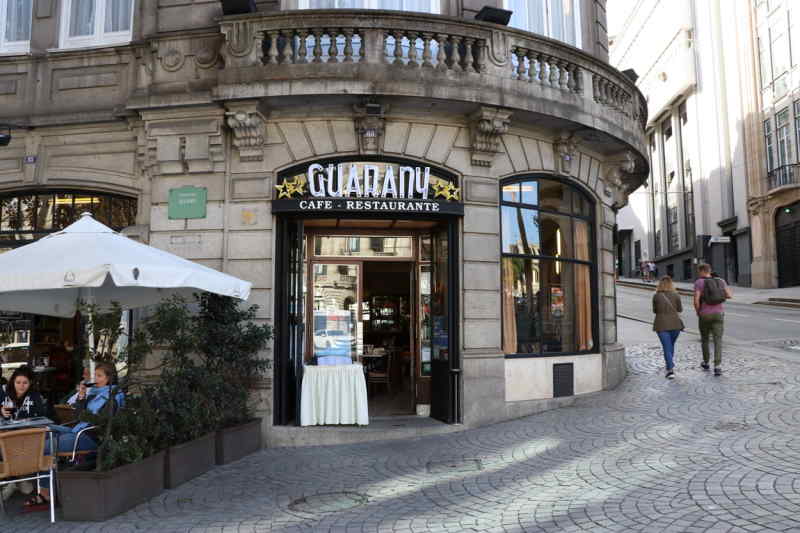 A building featuring a restaurant, showcasing outdoor seating and large windows for a welcoming atmosphere.