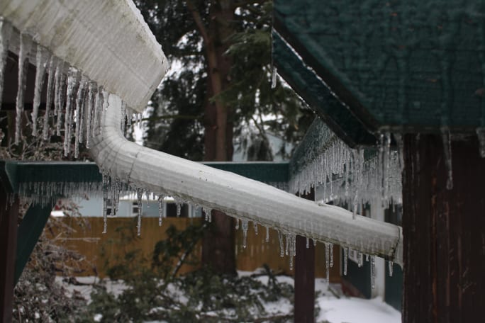 A drain-pipe and trellis covered in ice