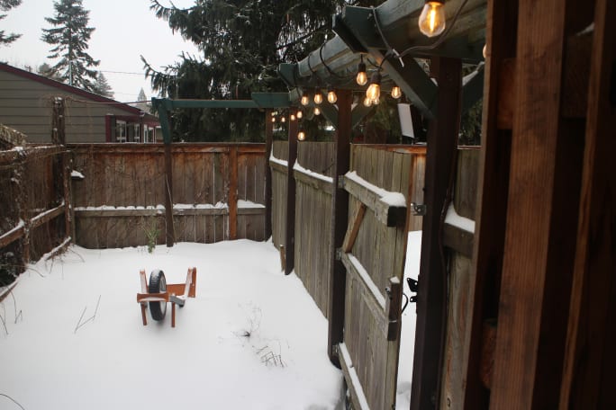 A small courtyard with an upside down wheelbarrow mostly buried in snow