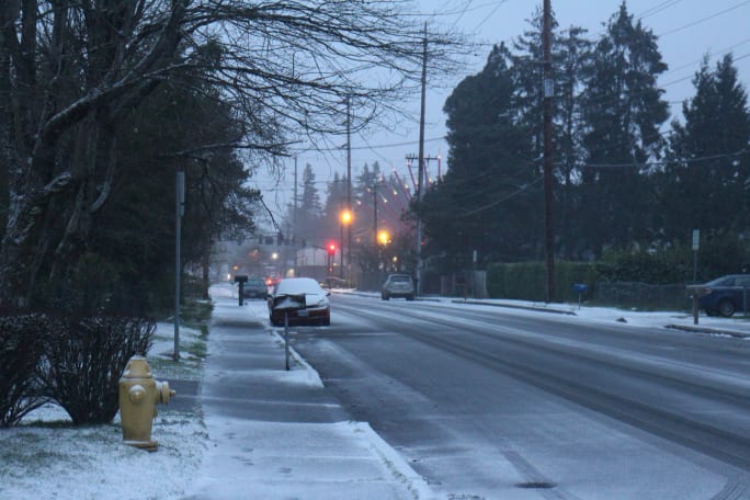 A street in the evening with a dusting of snow and some street lamps