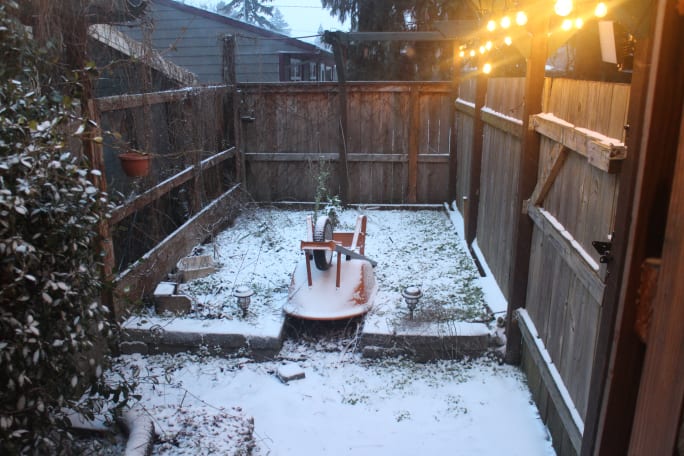 Small courtyard with an upside-down wheelbarrow and a little snow