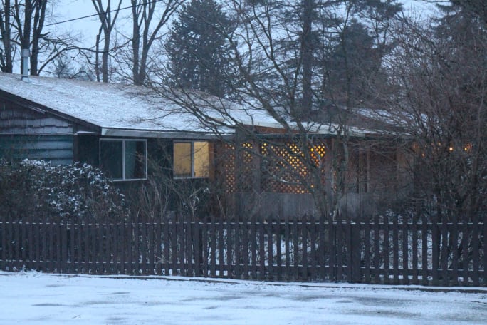 A house with a dusting of snow and some lights on inside