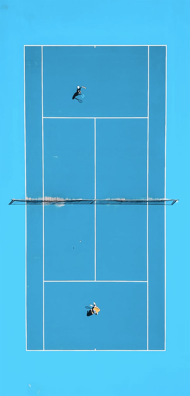 Bird's-eye view of tennis game on blue clay