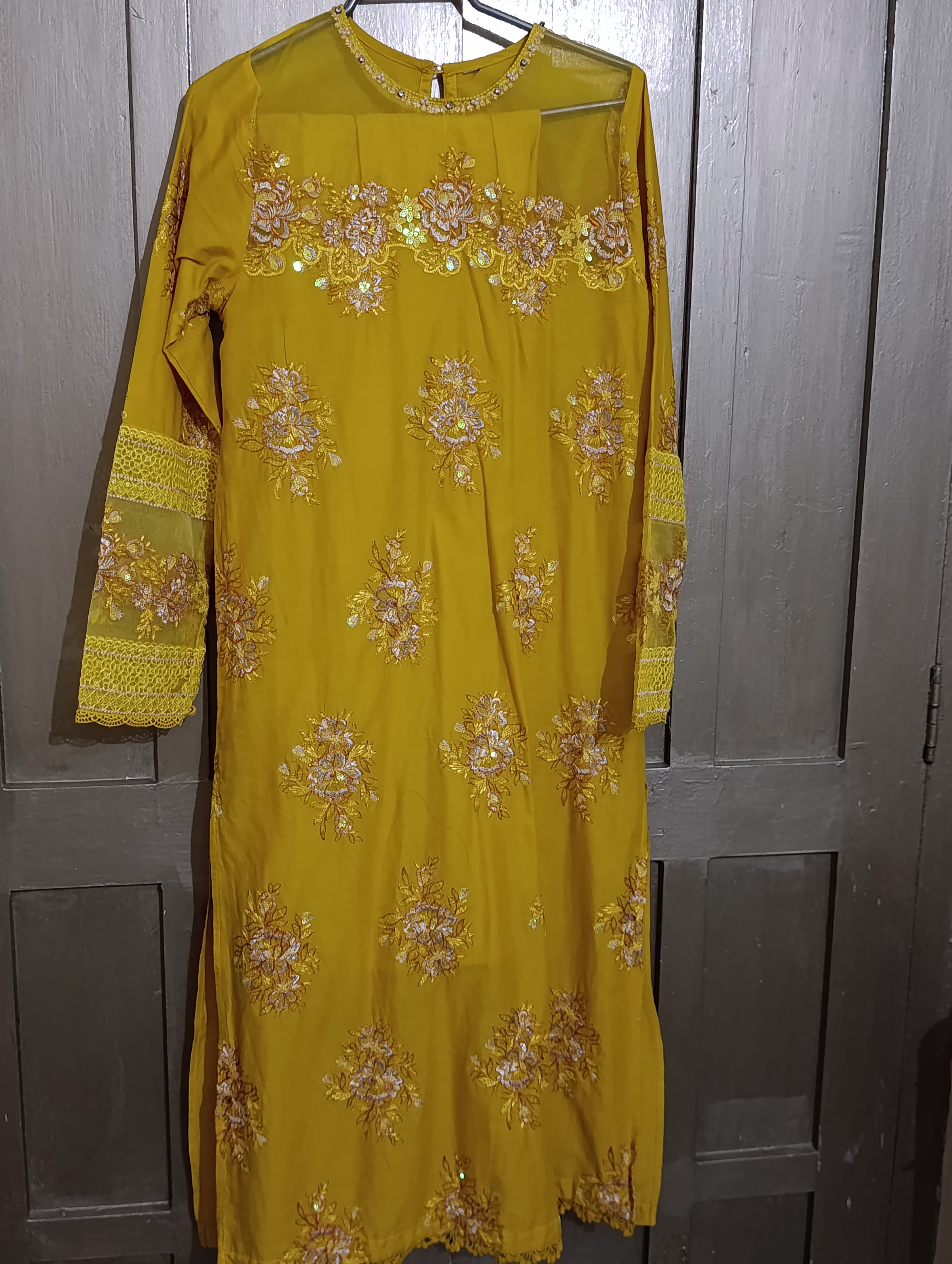 Mustard-yellow embroidered kurta featuring intricate floral motifs in gold and silver thread, with elegant lace detailing 