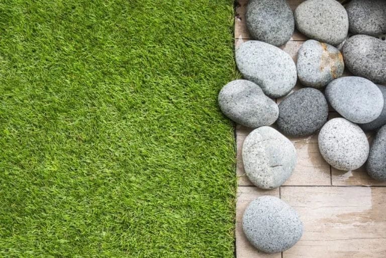 Aménagement paysager moderne associant une plateforme en bois et une surface en gazon artificiel.