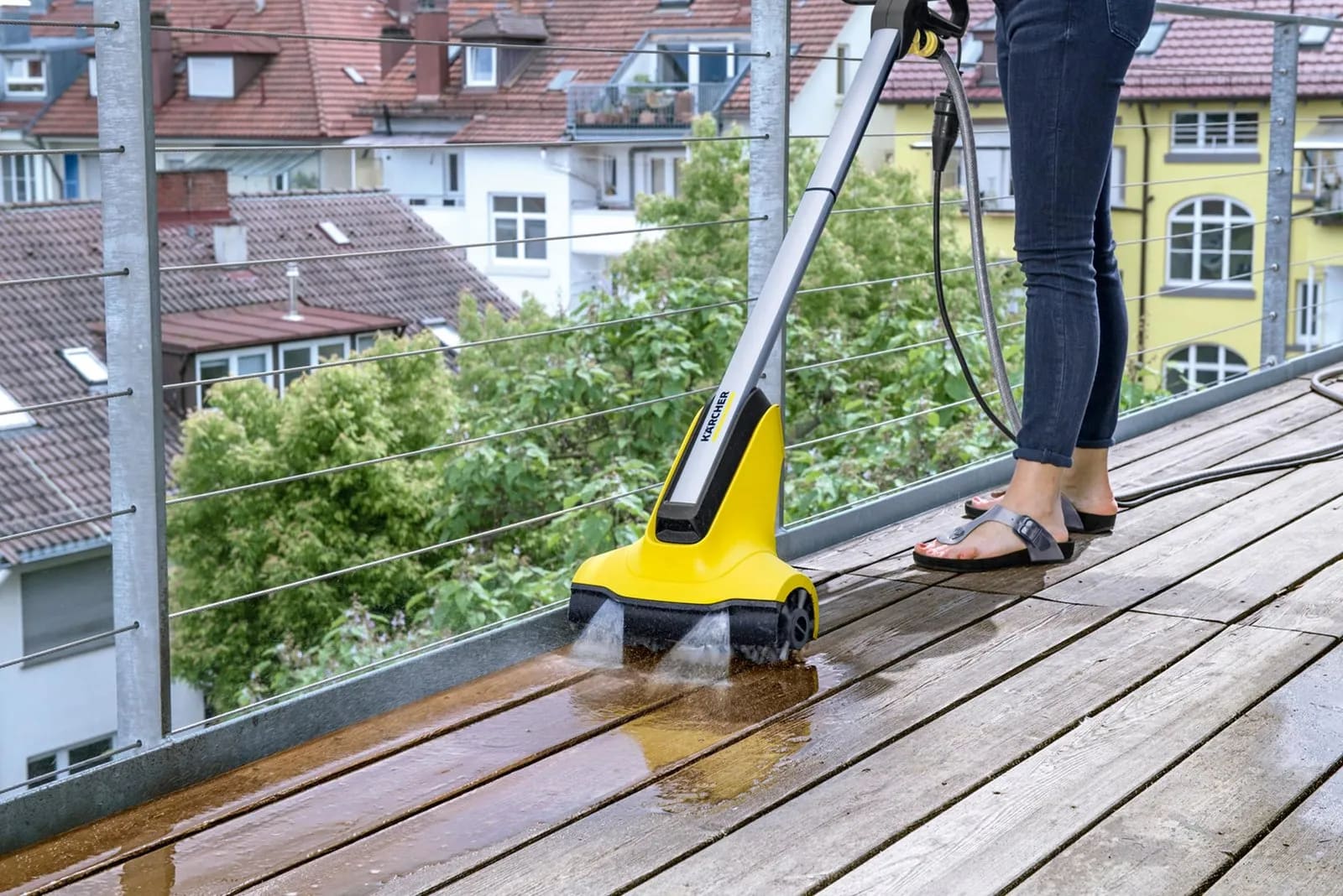 Nettoyage en profondeur d'une terrasse en bois à l'aide d'un balai brosse et d'eau savonneuse.