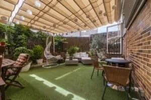 Terrasse en bois naturel bordée d'un gazon synthétique verdoyant dans un jardin.