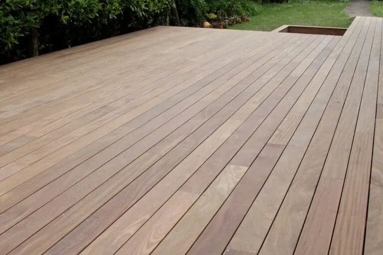 Terrasse en bois exotique entourant une piscine sous le soleil radieux.