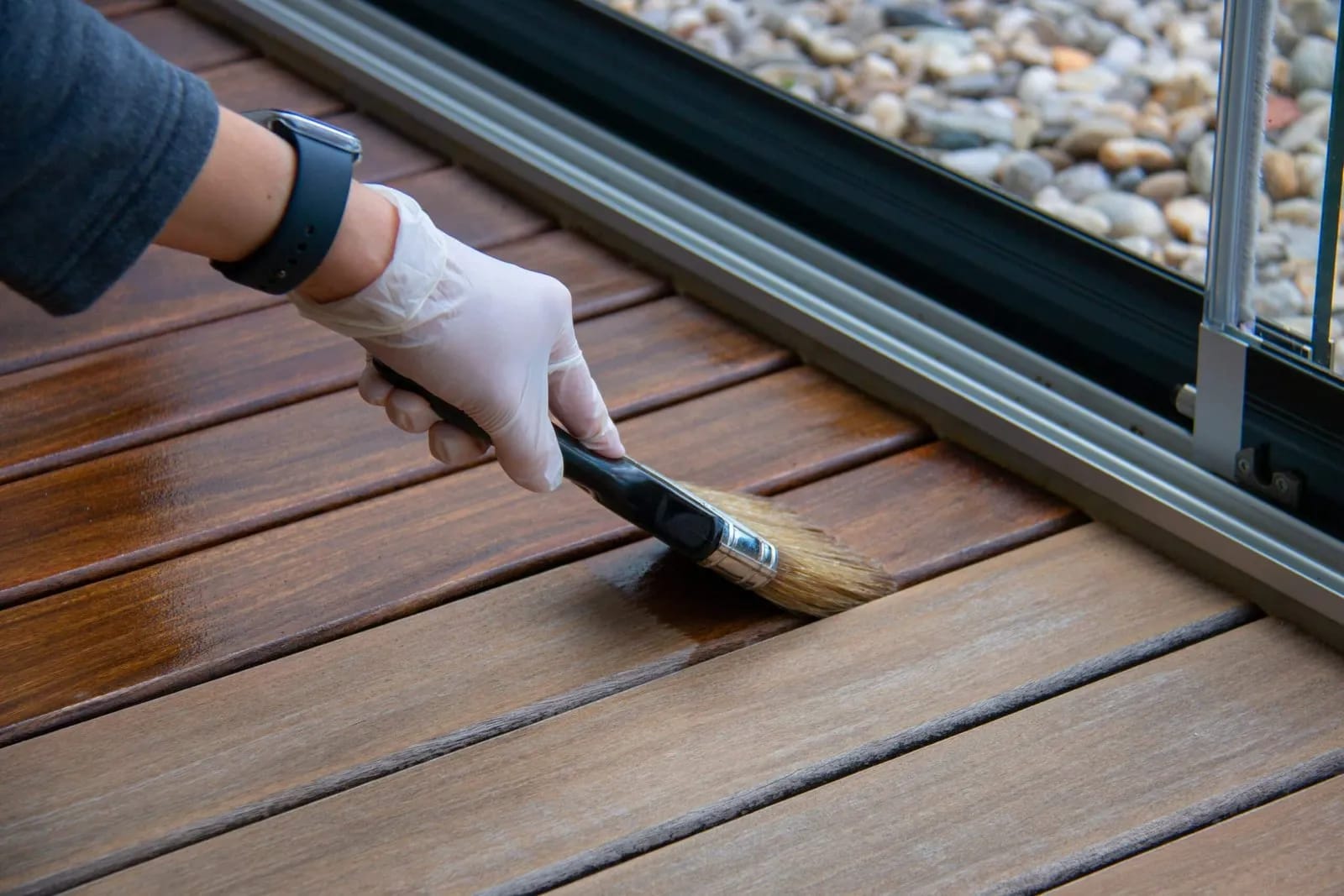 Gros plan sur le dégrisage d'une terrasse en bois exotique retrouvant son éclat d'origine.