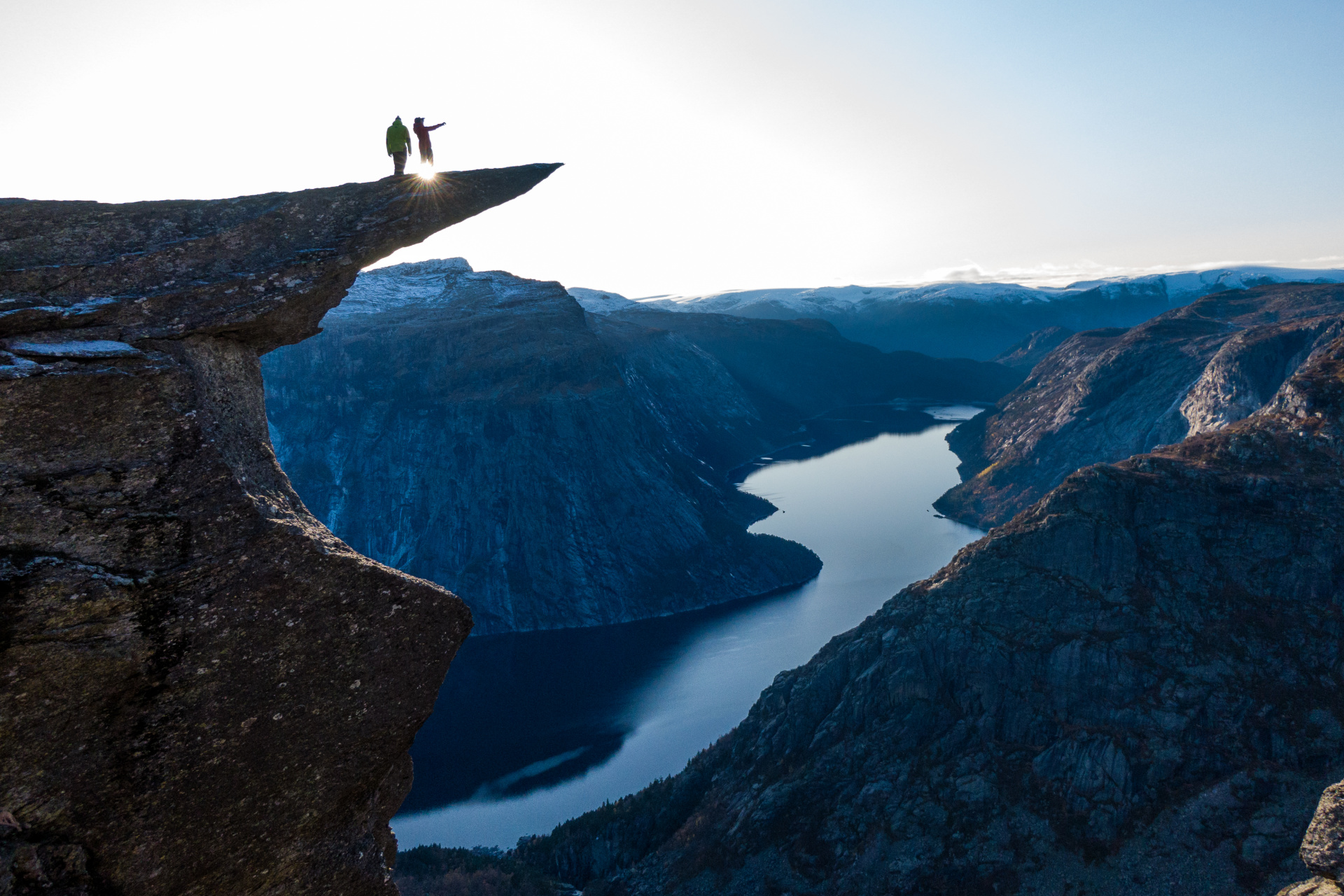 Trolltunga with two people on top, looking out over the fjord.  