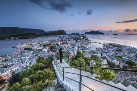To personer som går opp trapper og som ser på utsikten over Ålesund by.