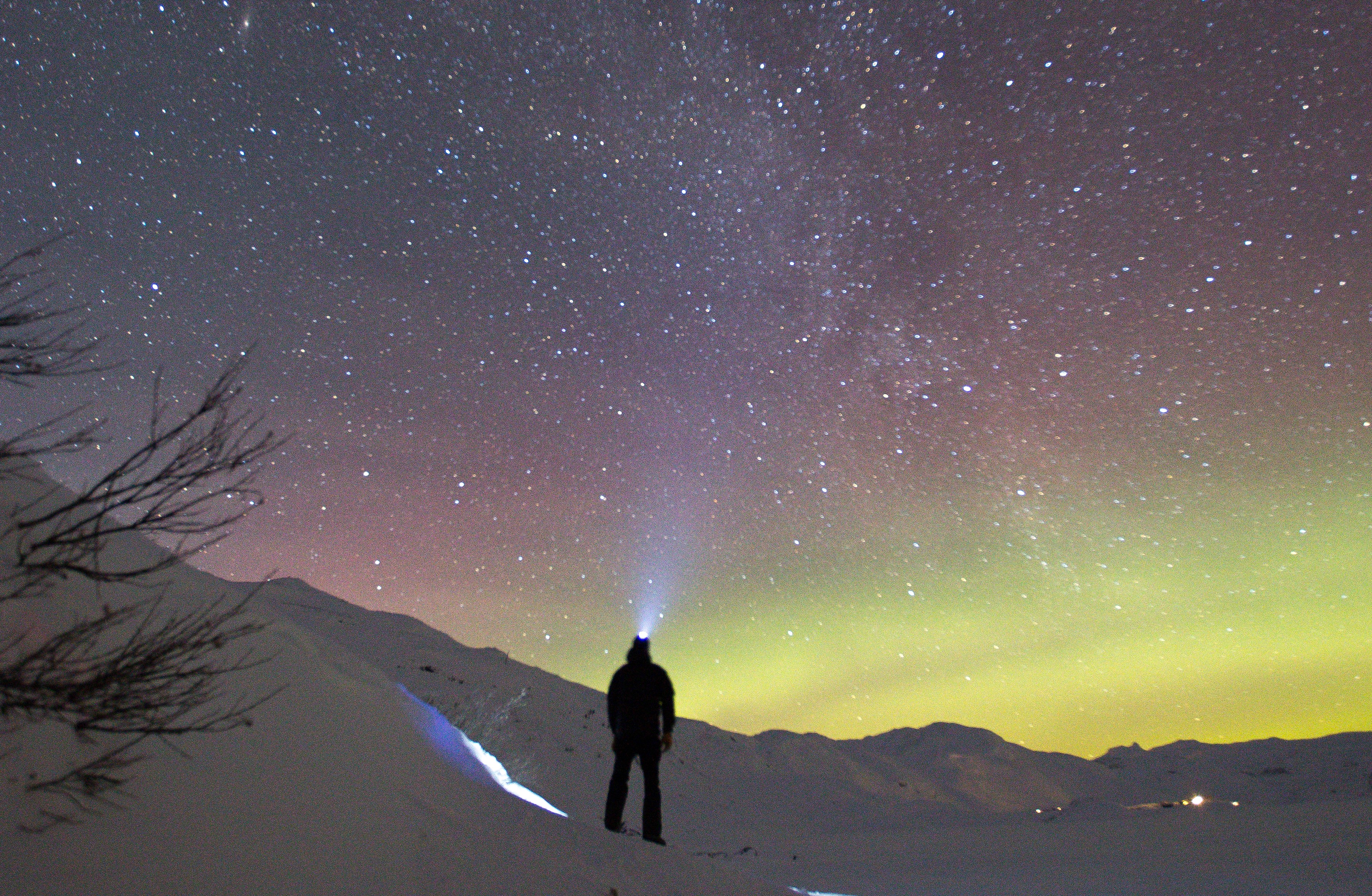 A starry winter night with mountains in the distance and cabin up