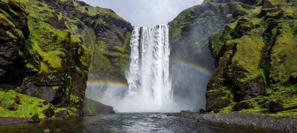 Majestic Waterfall Rainbow Over Mossy Cliffs — desktop wallpaper